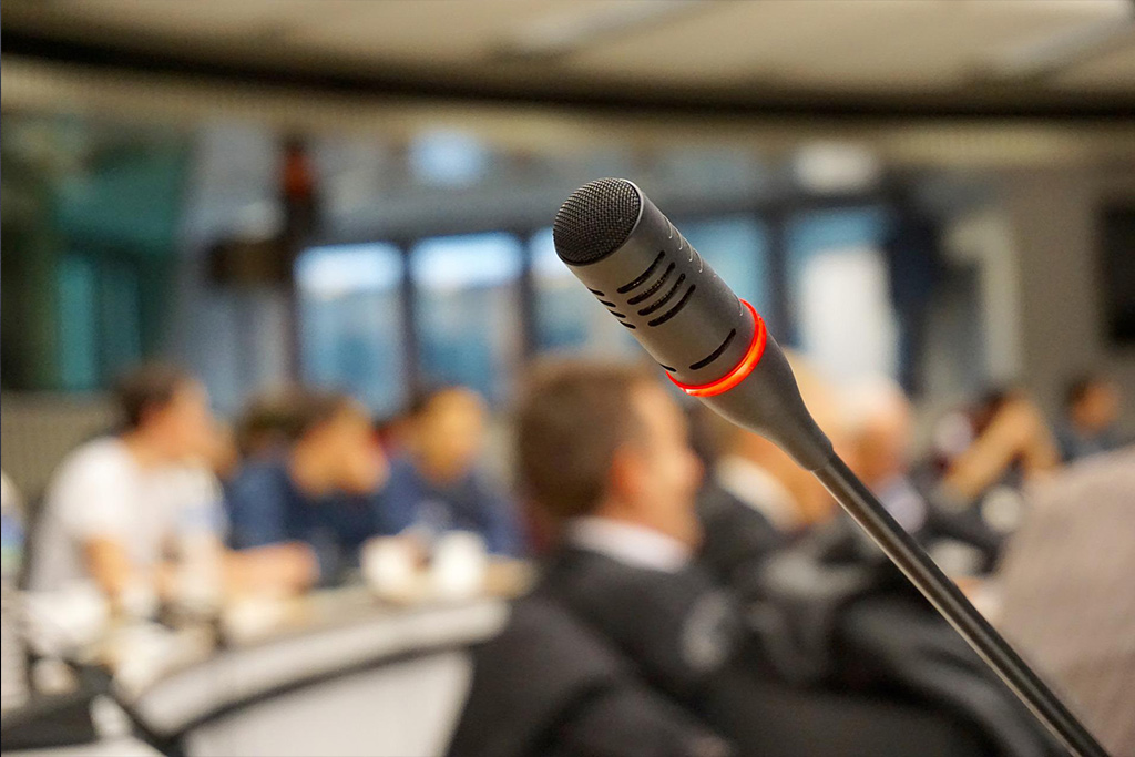 Mikrofon, im Hintergrund Zuhörer