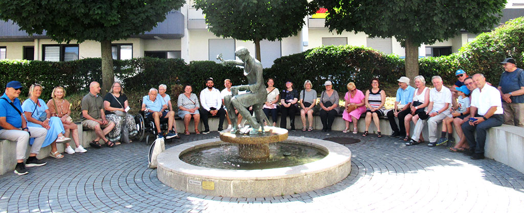 Die Teilnehmenden an der Salamander-Stadtführung sitzen vor dem Schusterbrunnen