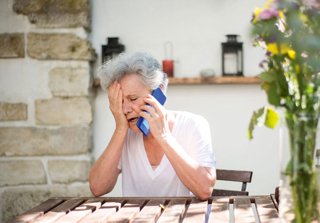 Verzweifelte Frau mit Telefonhörer am Ohr