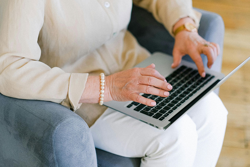Sitzende Frau, die auf die Tastatur eines Laptops tippt