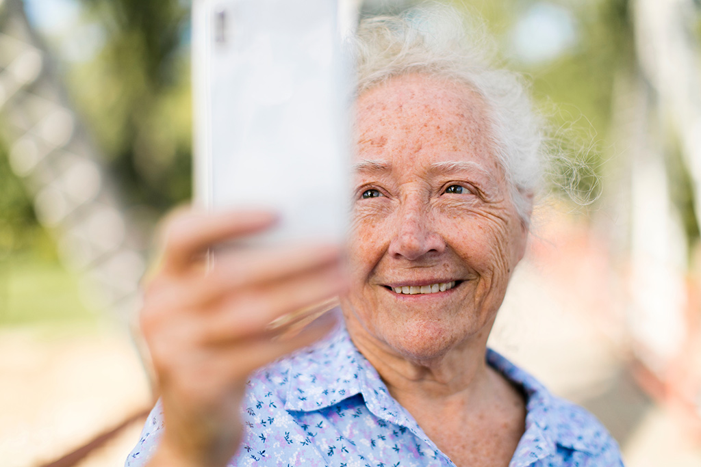 Ältere Dame hält ihrHandy hoch